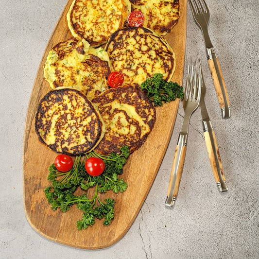 Kartoffelpuffer auf einem Holzbrett garniert mit Petersilie und Kirschtomaten
