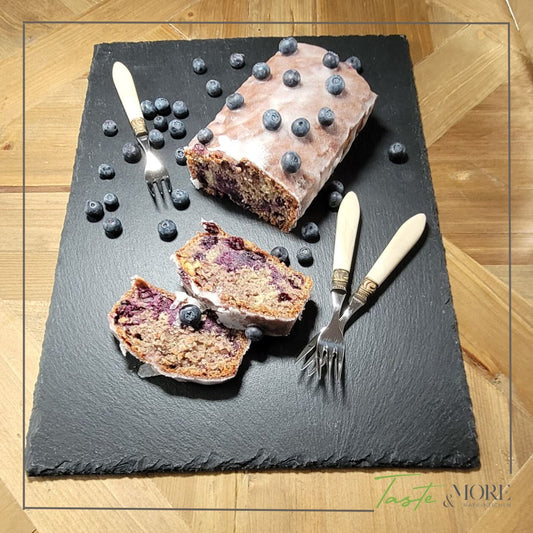 Rührcake mit Blaubeeren auf Schieferpalatte auf einem Holztisch