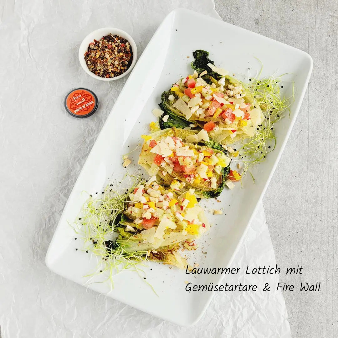 Lauwarmer Lattich mit buntem Gemüsetartare, verfeinert mit Fire Wall Gewürzmischung, frischem Parmesan und knackigen Nüssen - leichte, aromatische Vorspeise.