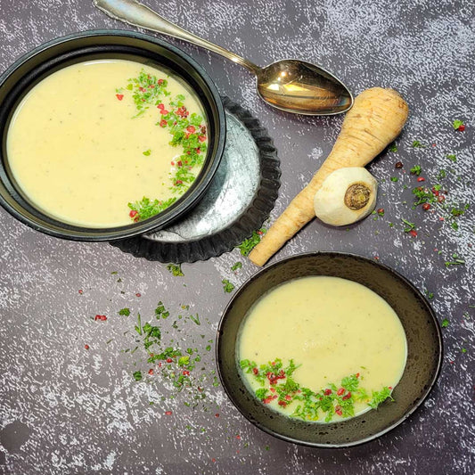 Pastinaken-Apfelsuppe in schwarzen Schalen garniert mit Peterli und rosa Pfeffer