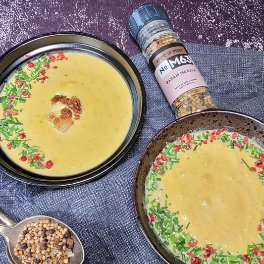 Geröstete Blumenkohlsuppe in schwarzen Schalen, garniert mit Schnittlauch und rosa Pfeffer