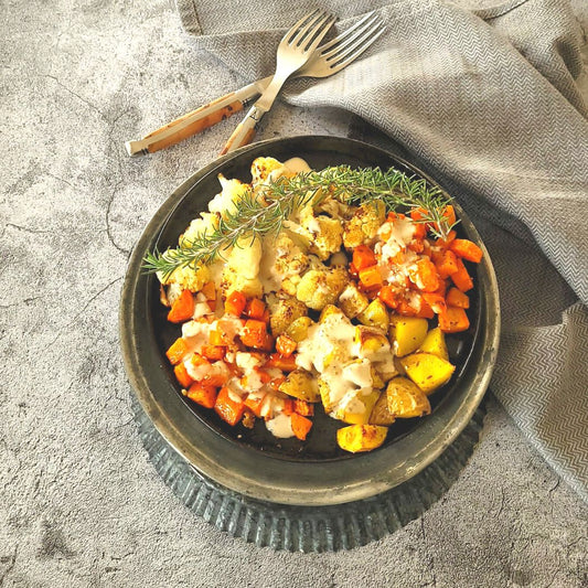 Blumenkohl, Karotten und Kartoffeln auf dunklem Teller mit Sesamsauce